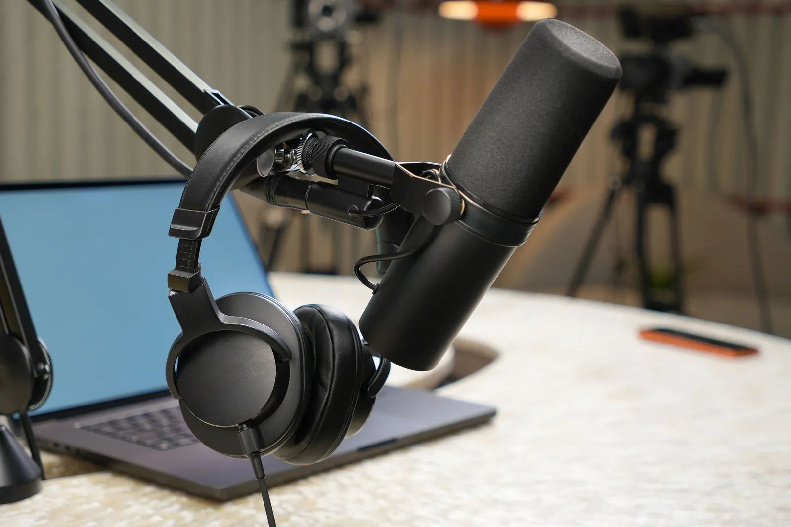 Podcast-Mikrofon und Monitor-Kopfhörer neben einem Laptop